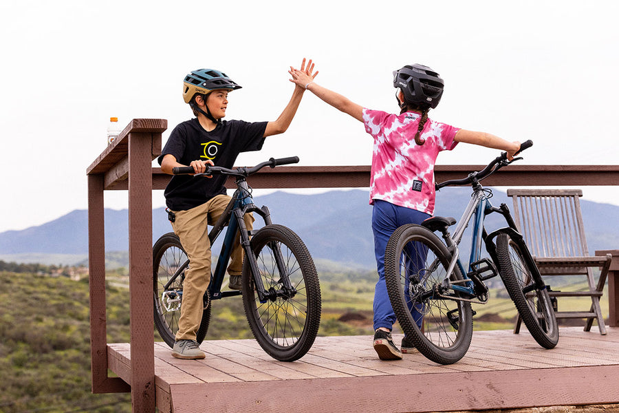 Two kids giving a high five at the top of a bike ramp