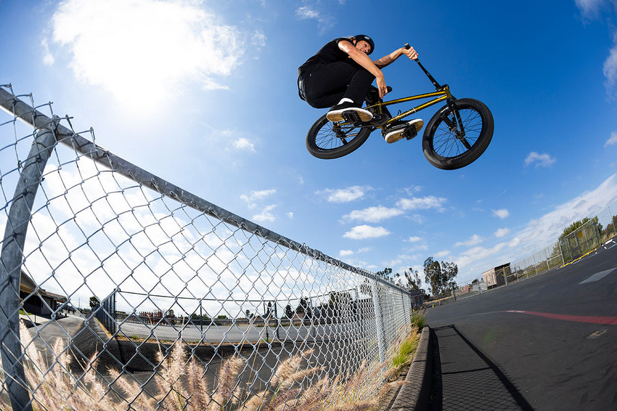 BMX biker jumping over fence